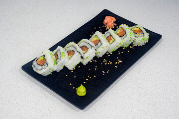 A plate of sushi with a green sauce on it
