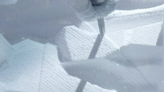 Close-up of automated robotic arm milling machine cutting a block of Styrofoam.
