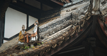 Fototapeta premium Chengdu, Sichuan, China. Figurines On Roof Of Temple. Chinese Architecture. Figurine Of Men Sitting At Table. Park On Grounds Of Wuhou Memorial Temple, Chengdu. Traditional Chinese Architectural
