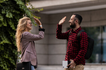 Friendly encounter between two colleagues sharing a high five outdoors