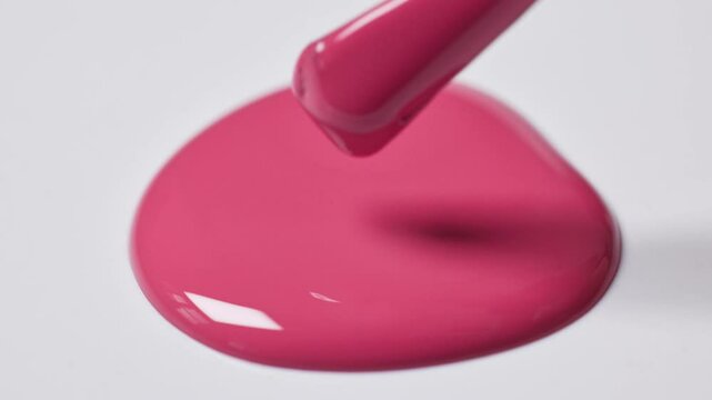 pink nail polish drop on white  background and a brush showing perfect smooth texture, closeup macro