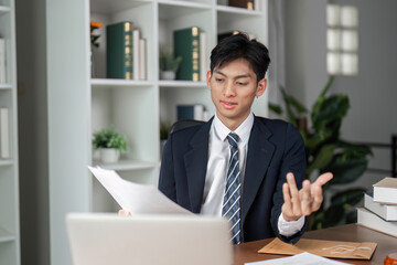 Fototapeta premium Young businessman explaining documents during a video call in a modern office environment.
