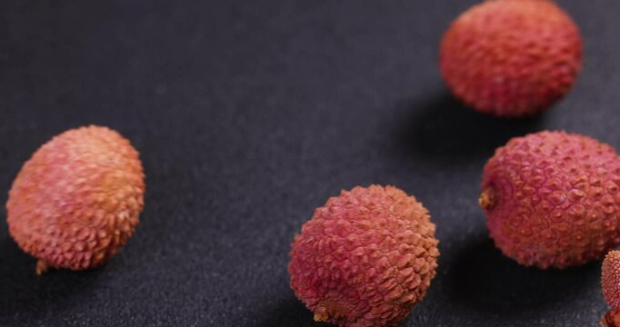 Lychees rolling on dark background