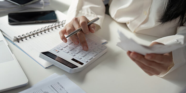 Tax Analysis. An individual conducting financial calculations and organizing tax documents at a desk with a calculator and notepad.