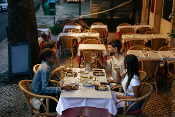 Friends enjoying dinner and wine at an outdoor restaurant in Lisbon
