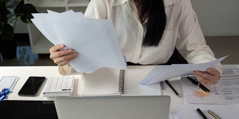 Tax Document Organization. An individual comparing tax documents and notes at their desk, ensuring...