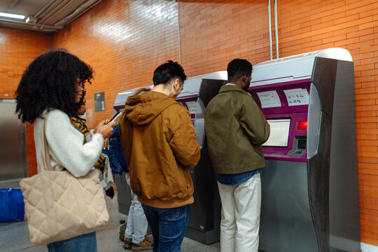 People using self-service ticketing machine in subway station