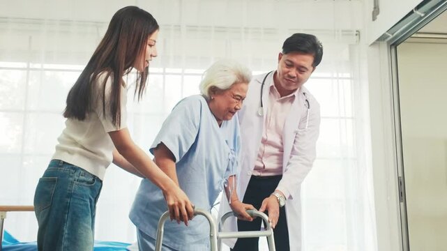 Doctor and caregiver assist an elderly woman using a walker in a rehabilitation setting. Senior care, physical therapy, mobility support, patient recovery in a healthcare facility. 4k real-time video.