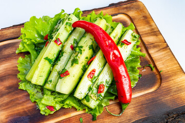 Fresh cucumbers and chili on a wooden platter with herbs