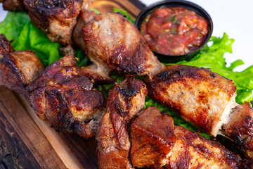 Juicy grilled meat skewers served with fresh salsa on a wooden platter