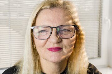 Peach fuzz and heavy makeup on senior woman face. Cat eye glasses