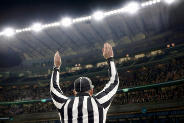 Football Referee Signaling Touchdown During Game Under Bright Stadium Lights