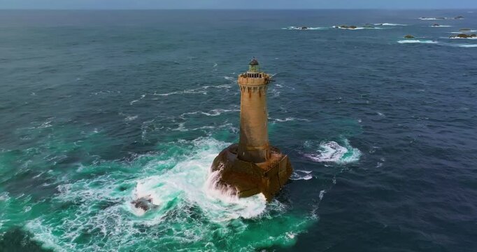 A rotating overhead shot of Phare du Four a lighthouse in Bretagne France. An ancient one standing far from the shore in the ocean and the first to meet huge waves