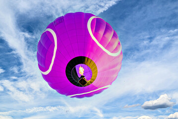 Colorful hot air balloon flying over blue sky with white clouds