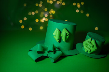 Paper origami leprechaun hats on green background with bokeh. Selective focus.