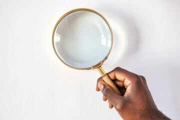 Black man hand holding magnifying glass on white background. Concept of search and analysis