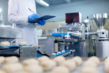 Technologist inspecting dough formation on automated pastry production line