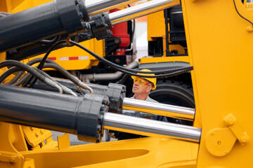 Machinery tractor mechanic checks hydraulic hose system equipment on excavator.