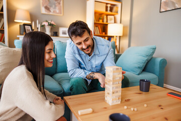 Couple having fun playing block stacking game at home