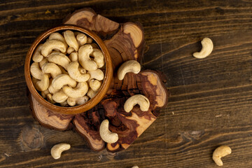 large cashew nuts are scattered on a larch board