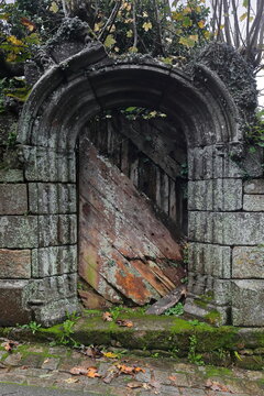 Remains of old wooden, paint-faded, round arch-topped door on the wall of an orchard on the west side of Rue Moal Street. Locronan-Brittany-France-327