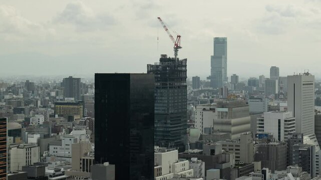 大坂で建築中の高層ビルとタワークレーンのタイムラプス映像（ズームアウト）