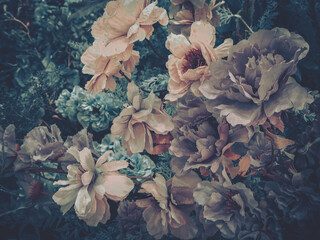 Artificial flowers bloom in muted tones. Delicate petals and soft colors create a vintage floral arrangement.  A cluster of blossoms evokes a sense of timeless beauty.