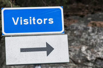 Visitors sign directing guests towards the entrance on a sunny day in a scenic location