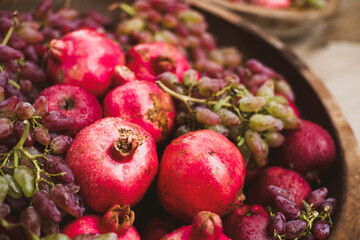 Bright juicy ripe pomegranates, pink grapes, red apples close-up, soft selective focus. Autumn fruit decor, harvest festival	