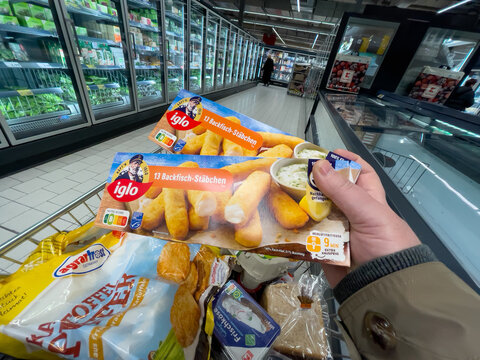 Germany Berlin February 19, 2025 A person is holding two packages of Iglo fish fingers in a shopping cart. The fish fingers are in a plastic bag