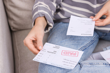 Paying bills. Woman with different invoices on couch at home, closeup