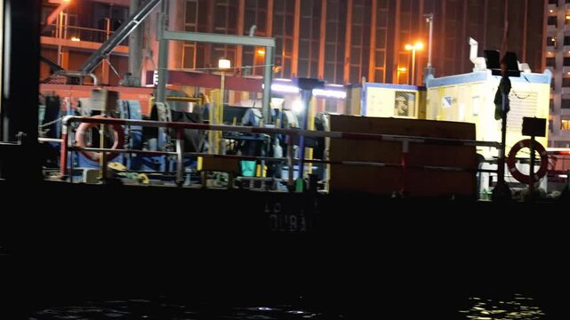 22.02.2025 Dubai,  UAE Workboats at night in Dubai's. Two workboats are active under bright lights in Dubai's waterfront, emphasizing the nighttime maritime operations critical for logistics and trade