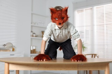 Quadrobics. Boy wearing fox mask and gloves on table indoors