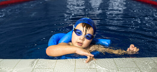 Child is engaged in swimming training, practicing strokes and gaining confidence in the water during a structured lesson