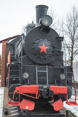 Naklejka premium An old locomotive steam locomotive with red wheels and a front star. Ancient steam equipment restored steam engine of a hundred years ago. High quality photo