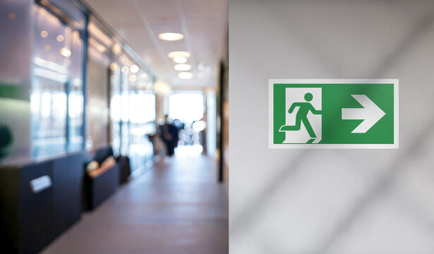 Emergency exit sign with right arrow on the wall of an office corridor. Attention, danger, emergency, fire sign.