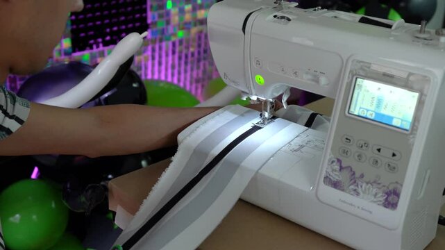 Person sewing fabric using machine, focusing on creating clothes with precision.