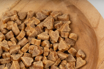 Mini pet food shaped like hearts in bowl close up, small dogs crunchy treats pile macro