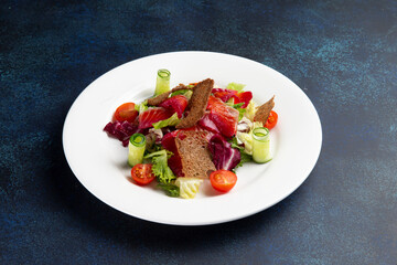 Salad with salmon in a plate on a dark background.
