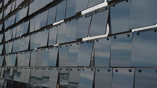 Rows of reflective plexiglass panels moving in tandem with the wind, slow motion medium shot