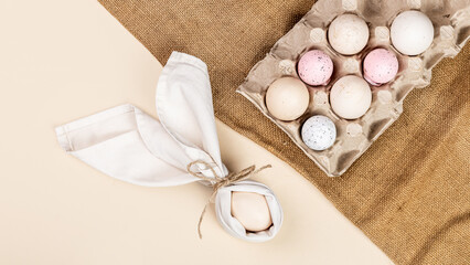 Napkin folded in the shape of rabbit ears with an egg inside, Farm natural eggs in an egg holder on...