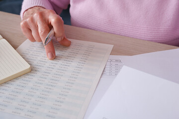 Senior woman reviewing financial documents and calculations at home