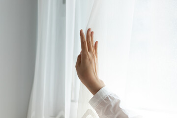 White gauze curtains are drawn by hand in interior rooms