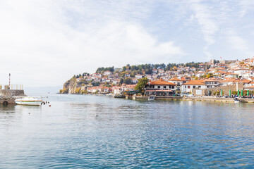 Picturesque coastal town Ohrid on a hillside by calm Lake Ohrid, clear sky, creating a serene and historical view.