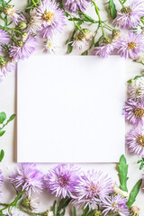 Obraz premium Vertical Asters springtime scenery, nature background. Festive holiday greeting card for Birthday, Woman or Mothers Day, blank copy paper and a greeting card. View from above.