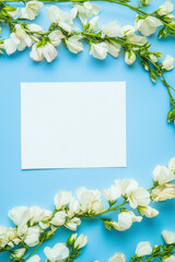 Vertical Snapdragons blue background. Festive holiday greeting card for Birthday, Woman or Mothers Day, blank copy paper and a greeting card. View from above. Flat layout.