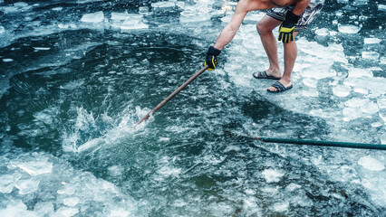 Man getting ready to swim in a frozen lake, man breaking the ice.