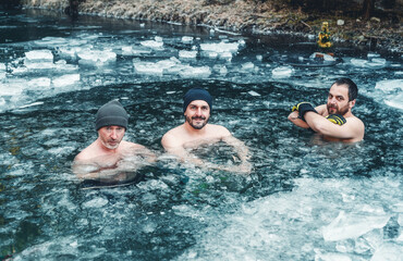 Three men hardening in a frozen pond. winter hardening.