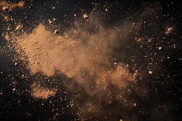 Brown powder dust spread out across a black dark background surface