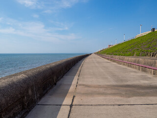 the long pedestrian promenade in North Blackpool in summer with the sea at high tide in summer...